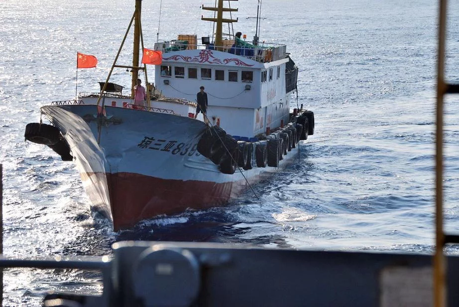 Un marin chinois utilise une gaffe pour essayer d'attraper l'antenne sonar remorquée de l'USNS Impeccable