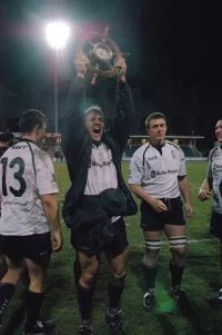 Un joueur de l'équipe de la Royal Navy brandit le trophée
