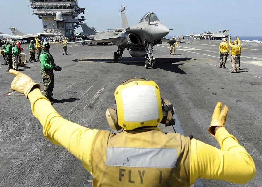 Un directeur de pont d'envol américain dirige un Rafale français vers la catapulte du Theodore Roosevelt